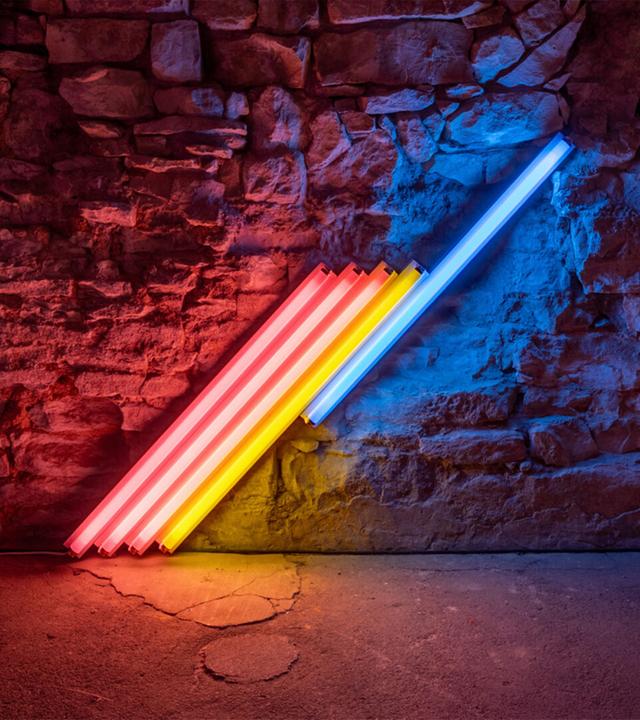 In einem abgedunkelten Ausstellungsraum sieht man eine Installation aus bunten, schräg nebeneinander angeordneten Neonröhren.