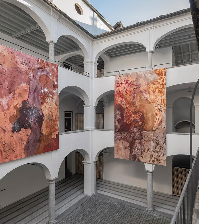 In einem Innenhof hängen zwei moderne Gemälde.