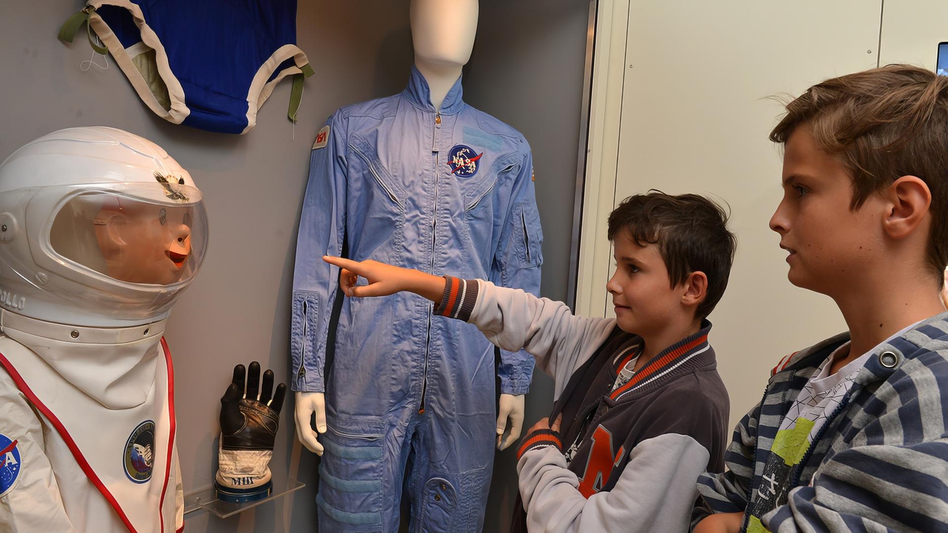 In einem Ausstellungsraum sehen sich zwei Kinder die Raumfahrtsexponate an.
