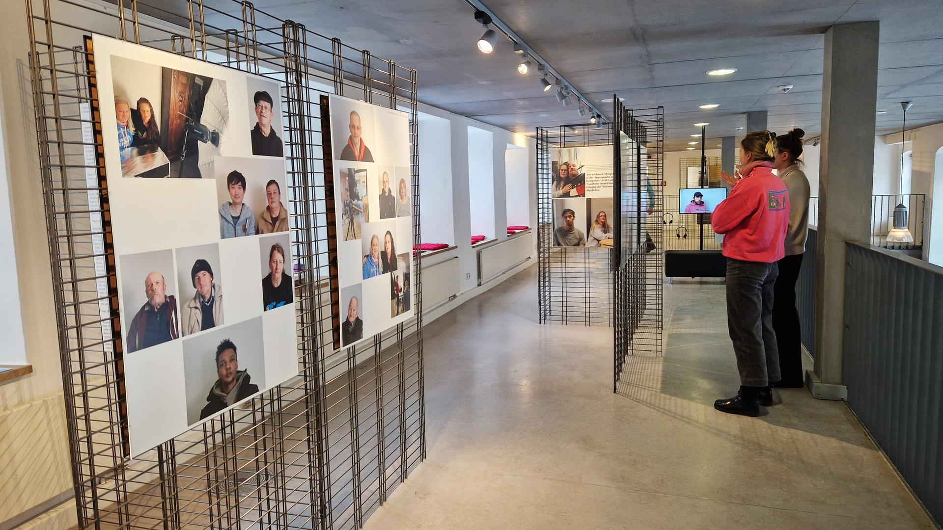 In einem Ausstellungsraum schauen sich zwei Frauen die Fotowände an.