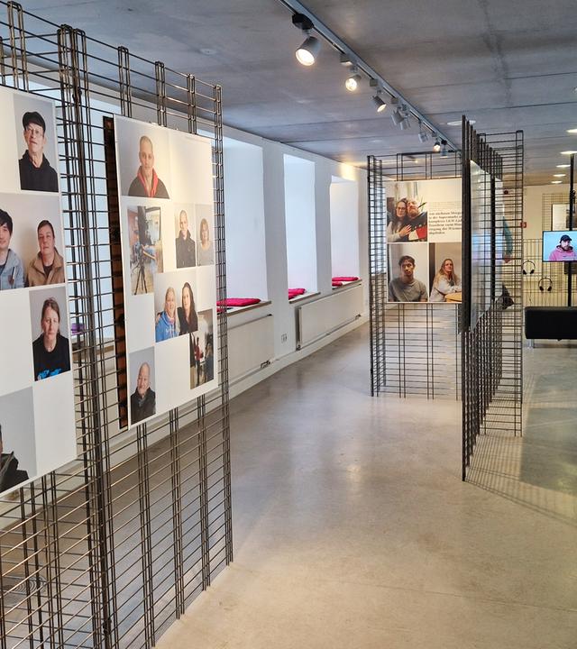 In einem Ausstellungsraum schauen sich zwei Frauen die Fotowände an.