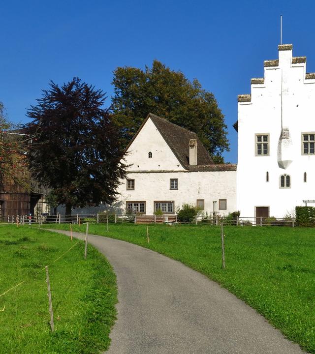 Man sieht ein historisches Gebäude in grüner Landschaft.