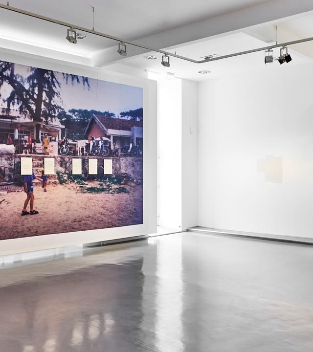Ein großformatiges Bild mit einer Dorfansicht aus Vietnam hängt in einem Ausstellungsraum