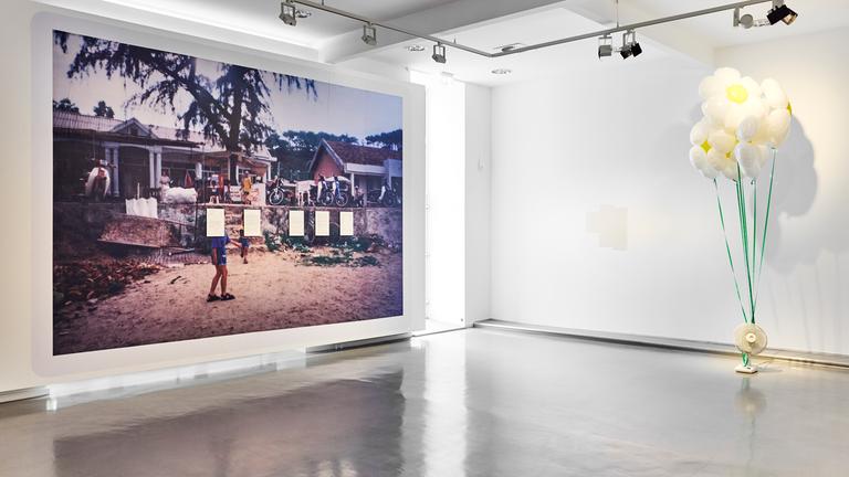 Ein großformatiges Bild mit einer Dorfansicht aus Vietnam hängt in einem Ausstellungsraum