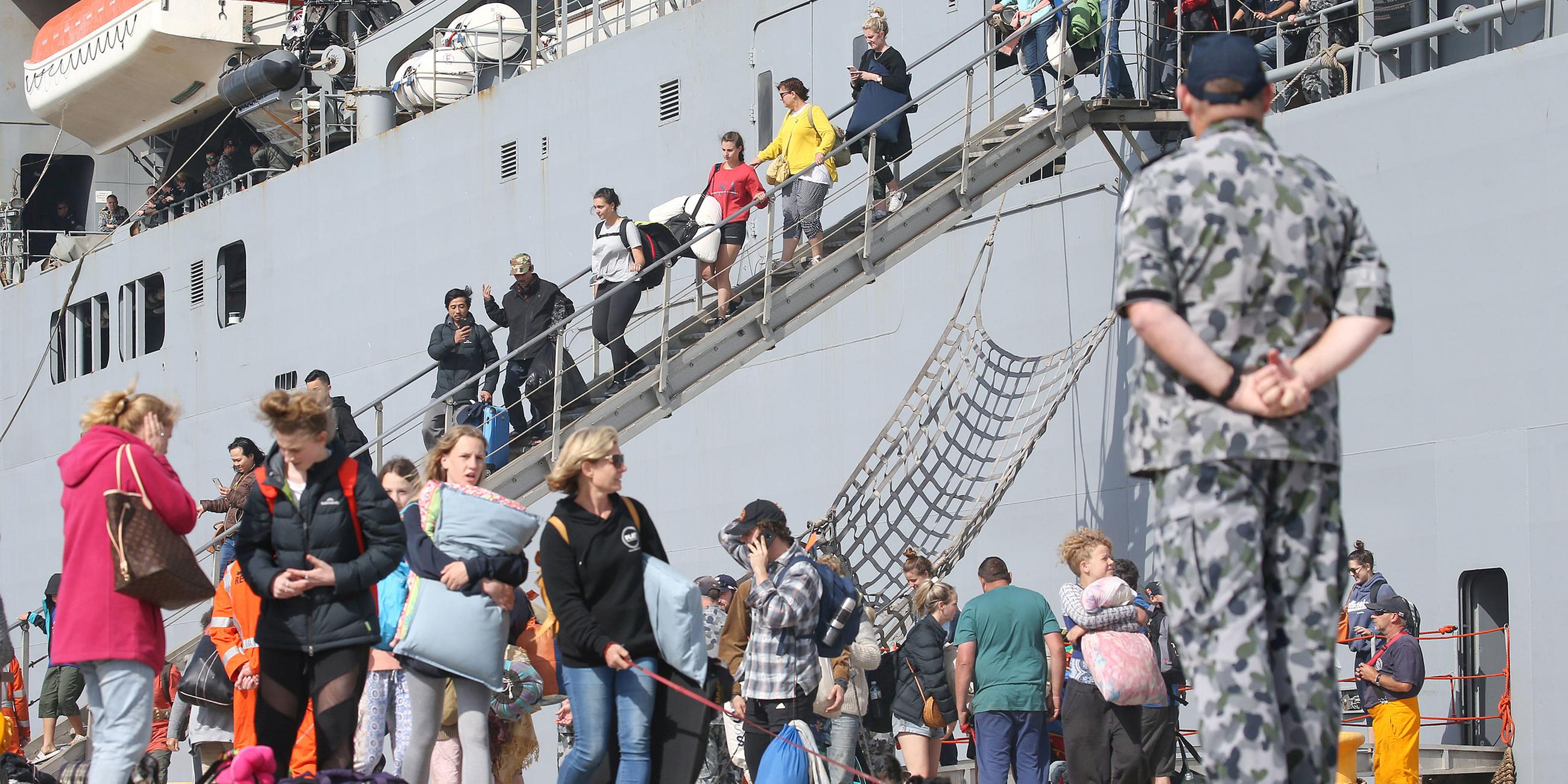 Evakuierte Australier und Touristen gehen vom Schiff im Hafen von Hastings, Australien.