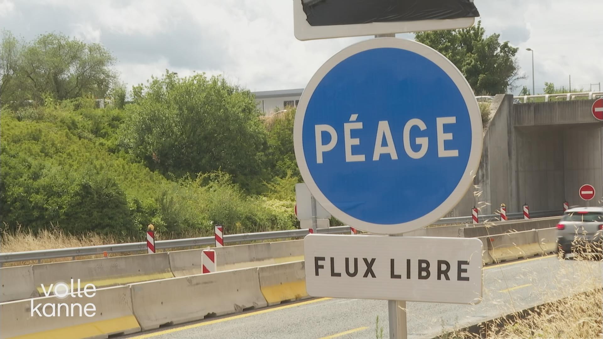Ein rundes, blaues Straßenschild mit der Aufschrift "PÉAGE" und darunter ein weißes, rechteckiges Schild mit der Aufschrift "FLUX LIBRE". Im Hintergrund sieht man eine Autobahn-Baustelle.