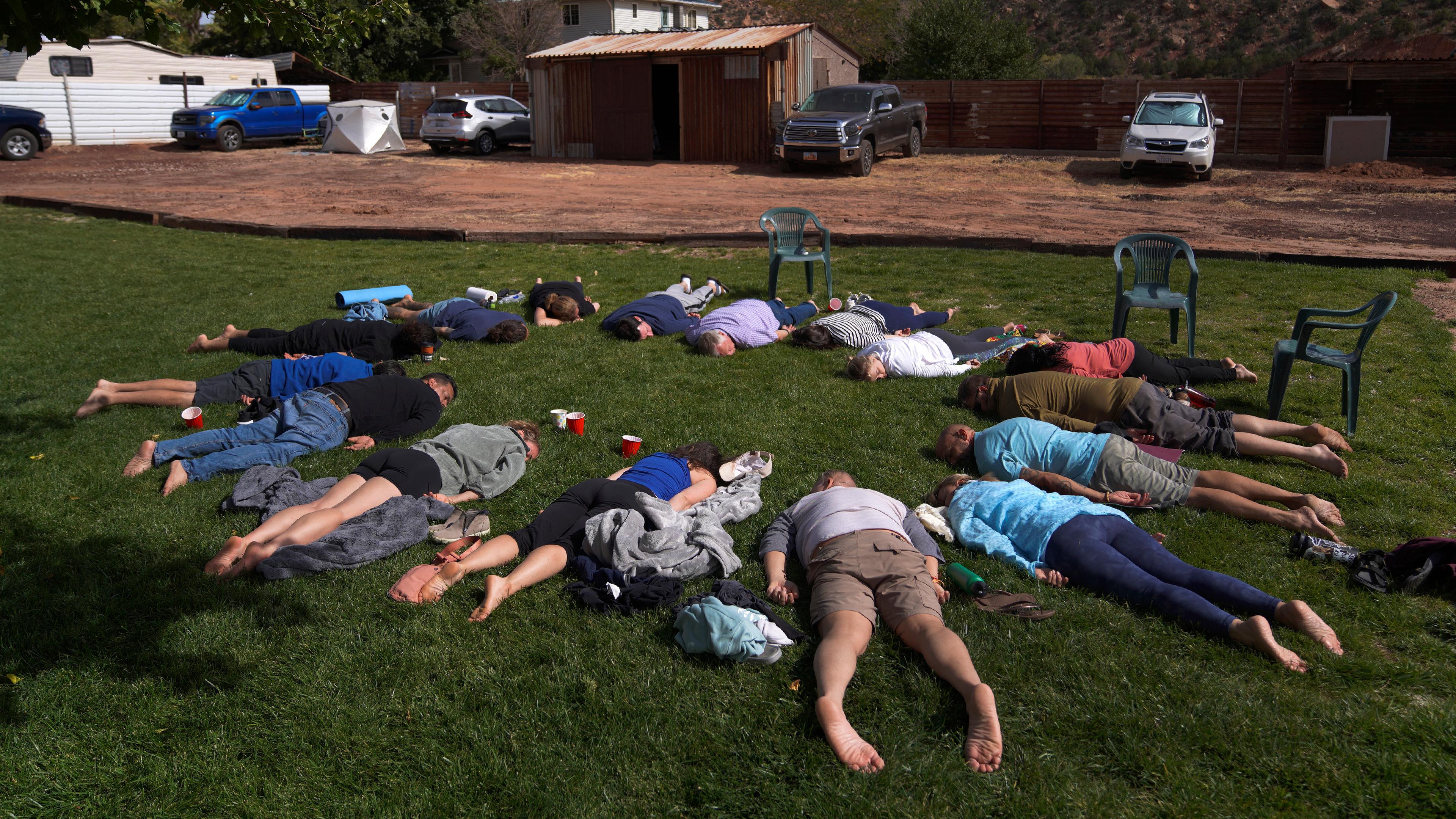 Teilnehmer legen sich während eines Integrationskreises bei einem Ayahuasca-Retreat in Hildale, Utah, mit dem Gesicht nach unten auf das Gras. Archivbild
