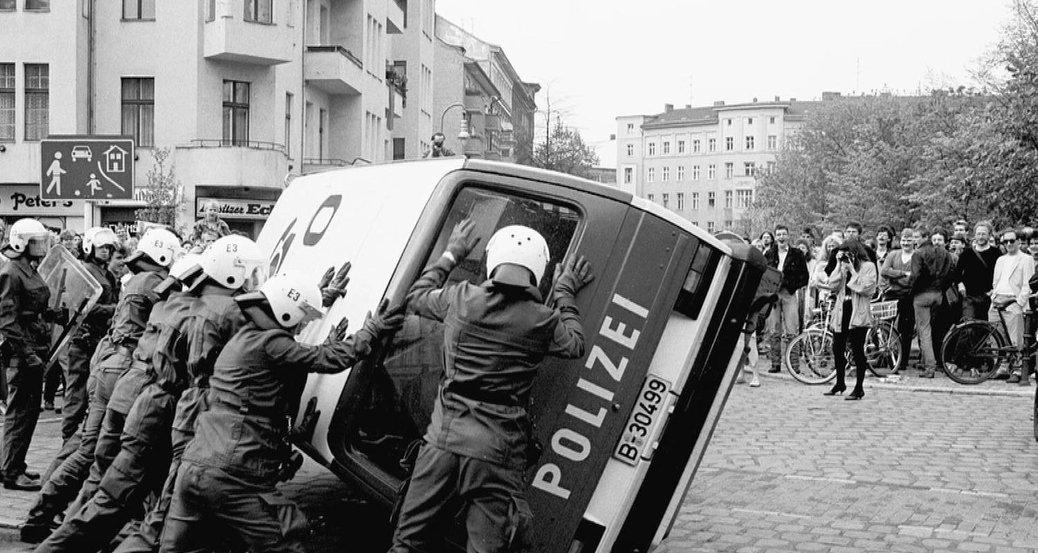 Mehrere Polizisten versuchen ein umgekipptes Polizeiauto aufzurichten. 