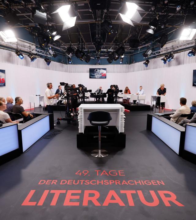 Blick ins ORF-Studio während einer Live-Sendung der Tage der deutschsprachigen Literatur  mit Jurytisch, Publikum, Kamerateam und Schriftzug 49. Tage der deutschsprachigen Literatur auf dem Boden.