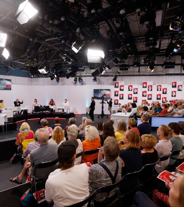 Blick ins vollbesetzte ORF-Studio während einer Jury-Sitzung der Tage der deutschsprachigen Literatur  mit Kamerateams, Publikum und großflächiger Porträtgalerie im Hintergrund.