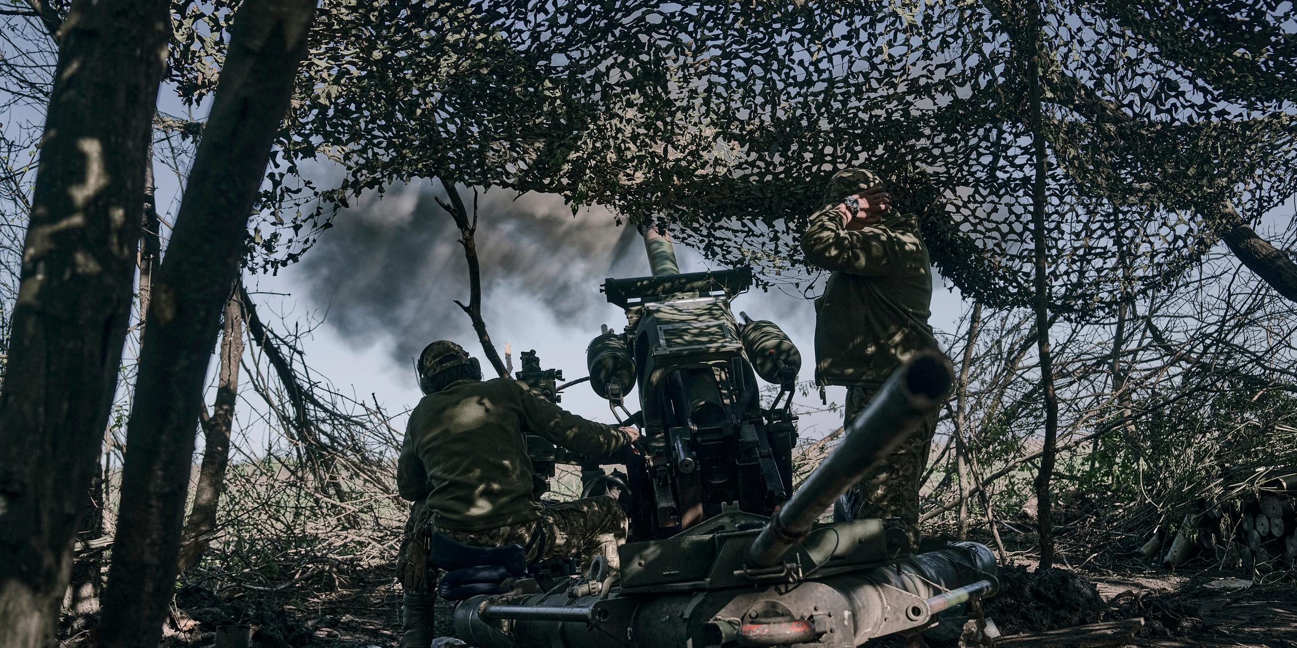 Ukrainische Soldaten feuern eine Kanone auf russische Stellungen 
