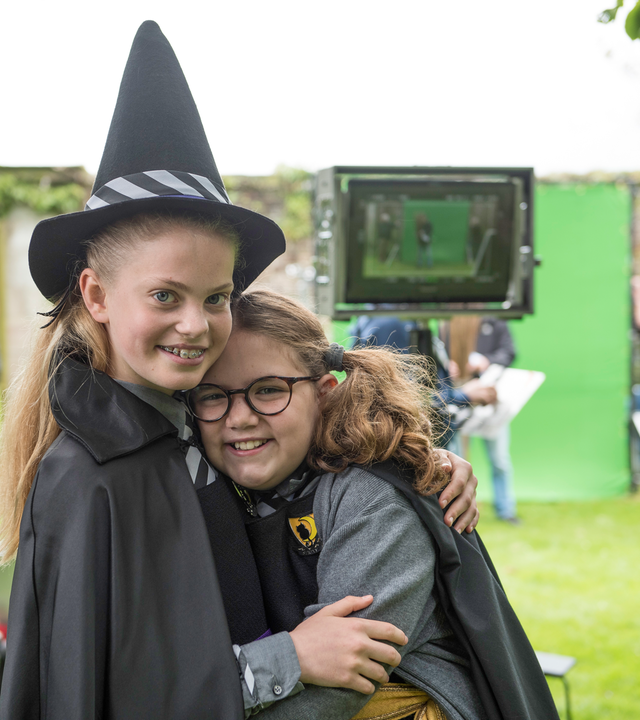 Esther Edel (gespielt von Jenny Richardson) und Maude Mondschein (gespielt von Meibh Campell) stehen im Hexenkostüm im Freien vor einer grünen Wand für die Computeranimation