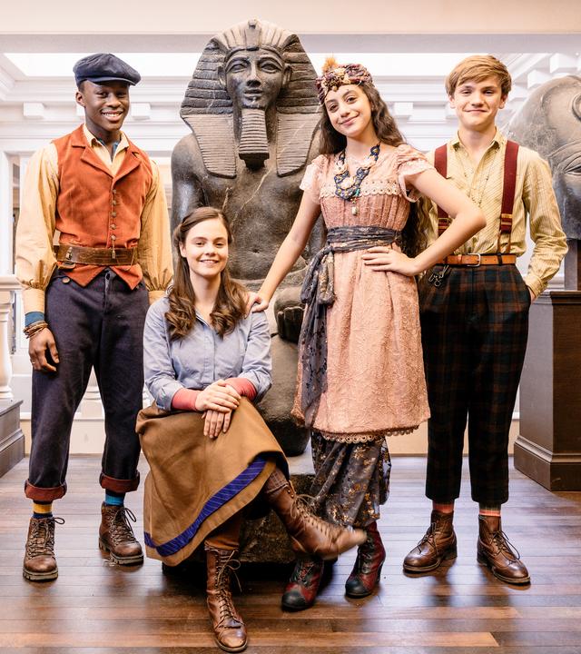 Nana, Frankie, Yasmina (stehend) und Eloise (sitzend) lachen nebeneinander im Museum in die Kamera.