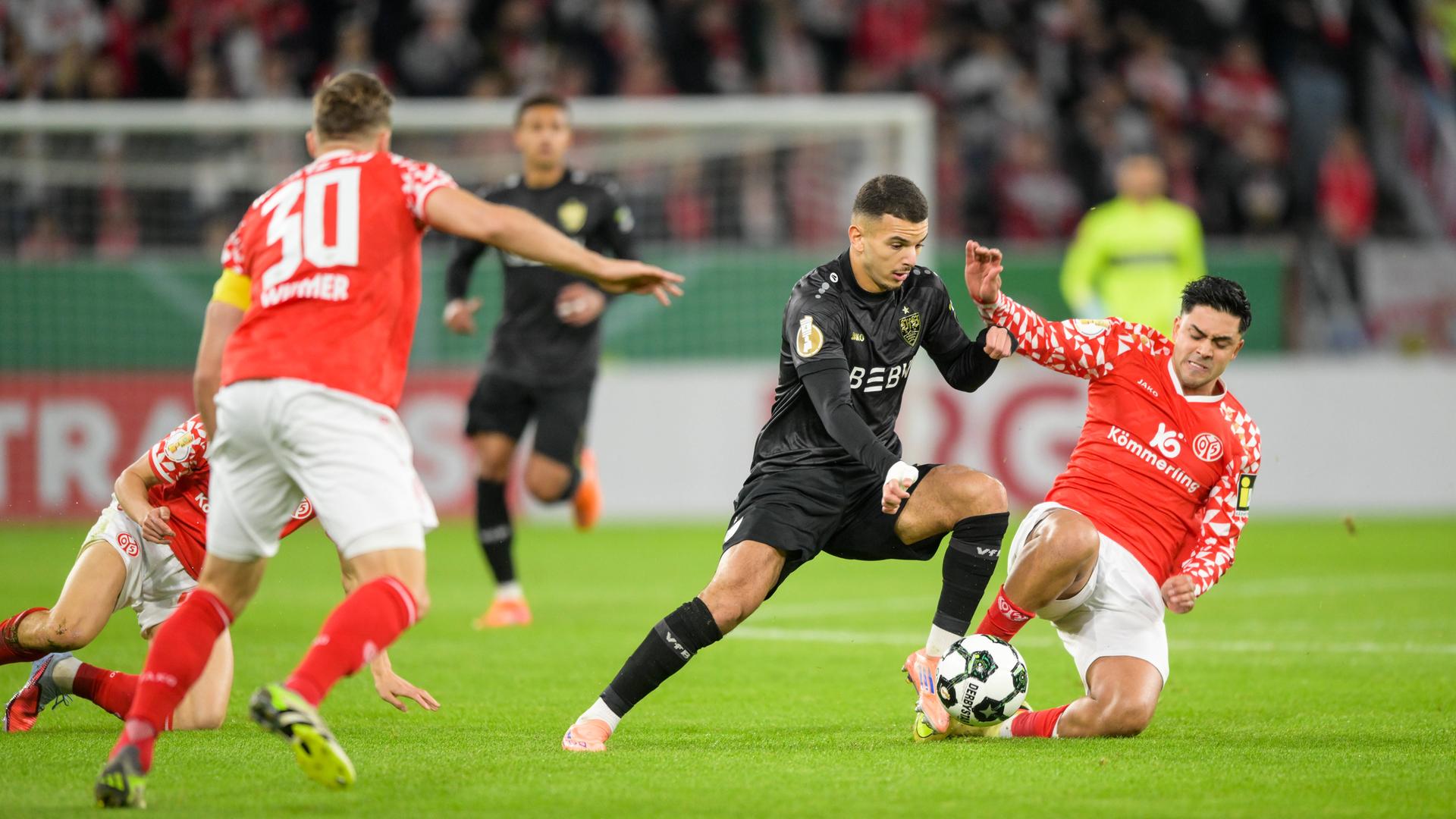 Fußballer Badredine Bouanani (Suttgart, 27, von links) und Nadiem Amiri (Mainz, 10) im rechten Bildbereich im Zweikampf um den Ball im Mainzer Stadio MEWA Arena.