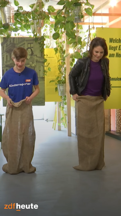 Baerbock beim Sackhüpfen mit einem Kinderreporter von logo