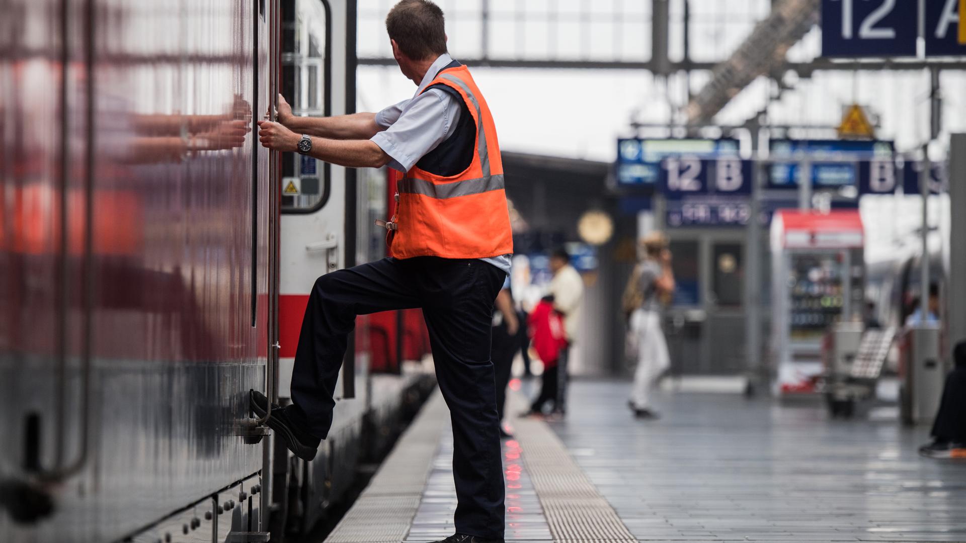 Ein Mitarbeiter der Deutschen Bahn steht im Hauptbahnhof neben einer Lokomotive.