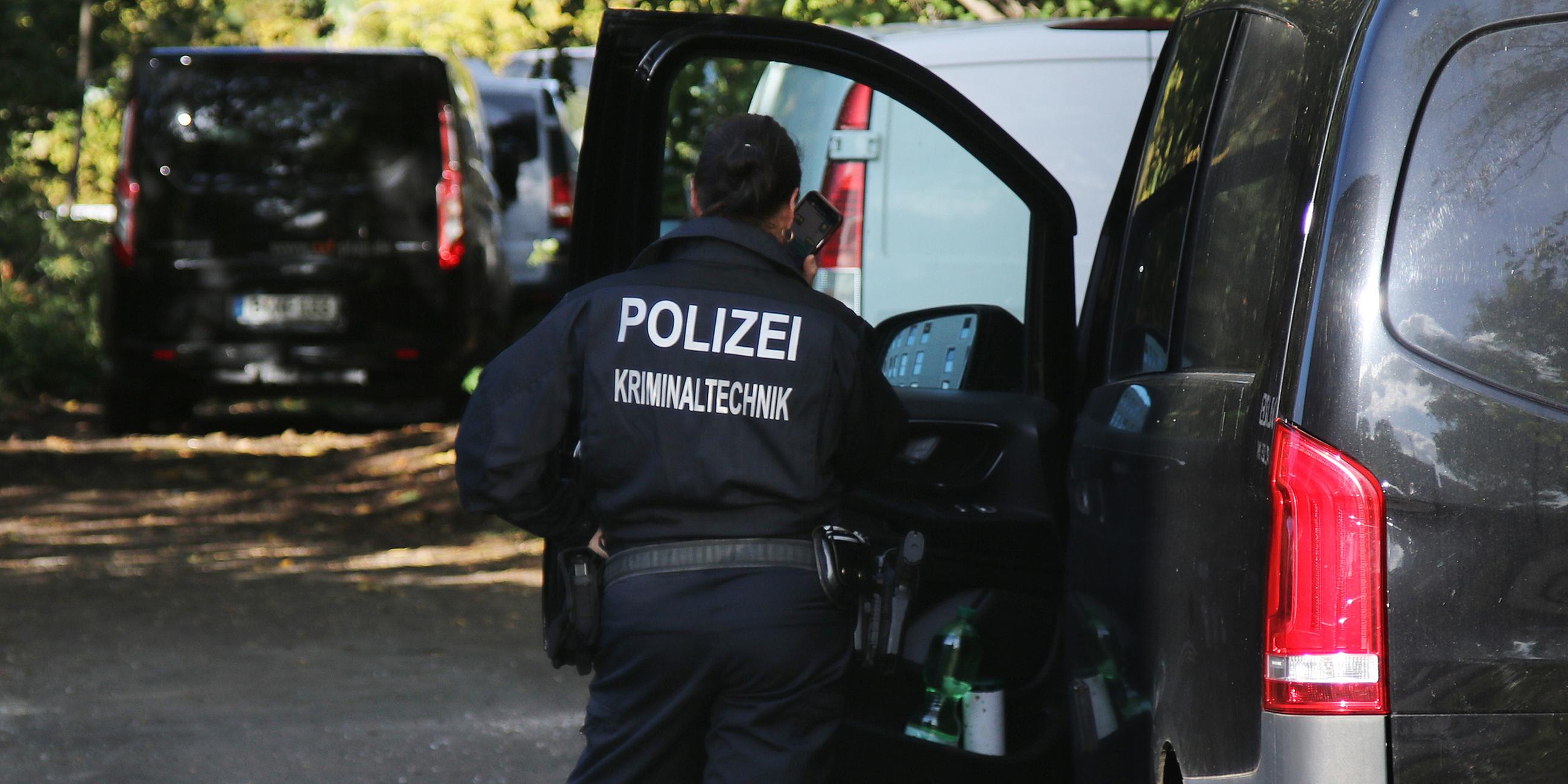 Eine Kriminaltechnikerin steht in der Nähe vom S-Bahnhof Hohenschönhausen neben Fahrzeugen der Polizei.
