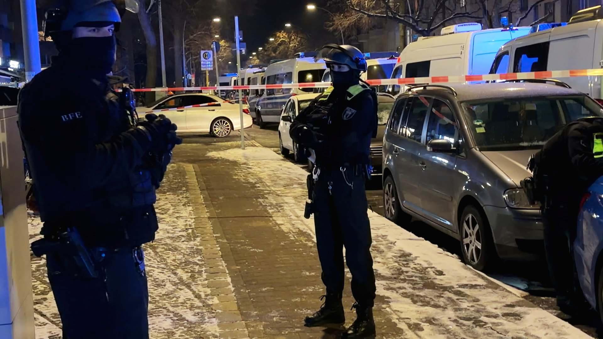 Zwei Vermummte Polizisten stehen vor Absperrband auf der Straße