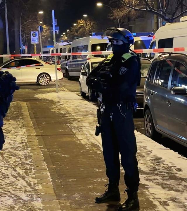 Zwei Vermummte Polizisten stehen vor Absperrband auf der Straße
