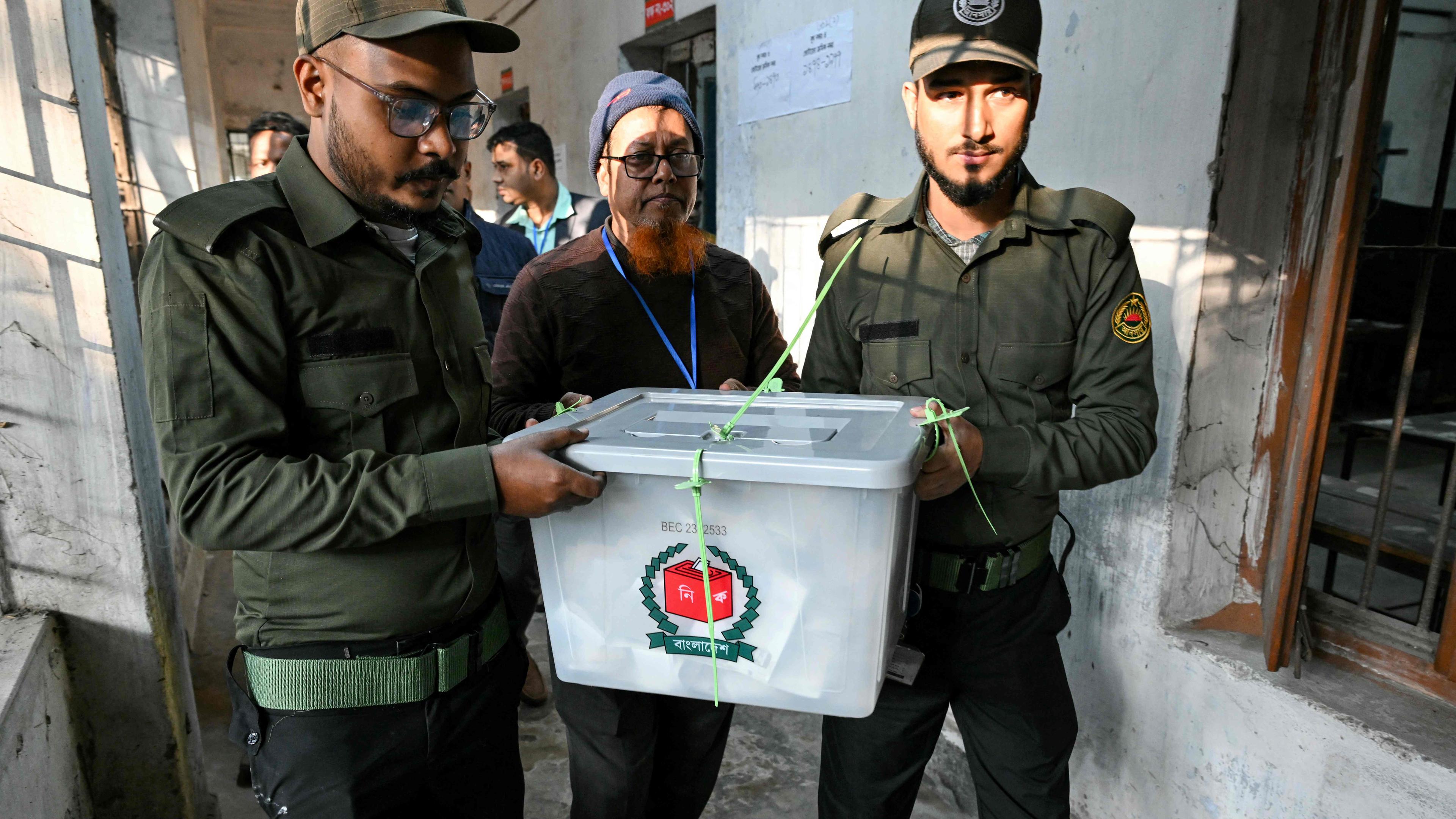 Sicherheitsbeamte tragen eine versiegelte Wahlurne bei sich