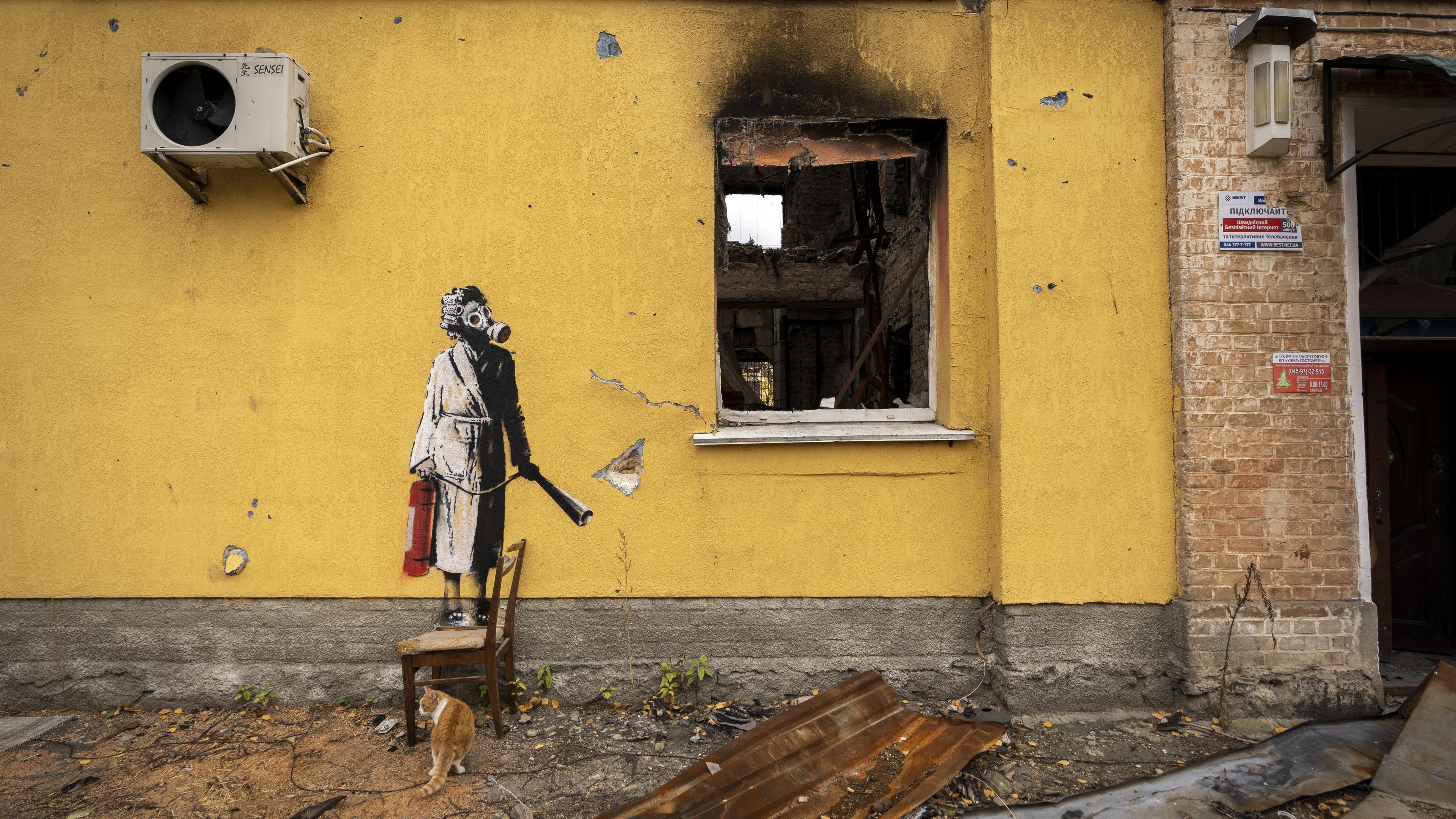 An einer Hauswand ist ein Bild des Streetart-Künstlers Banksy, das eine Frau mit Lockenwicklern und Gasmaske zeigt.