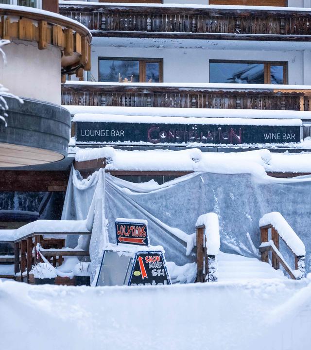 Dieses Foto zeigt die Fassade der Bar "Le Constellation“, in der das Feuer ausbrach, aufgenommen unter dem Schnee während eines nationalen Trauertages in Crans-Montana
