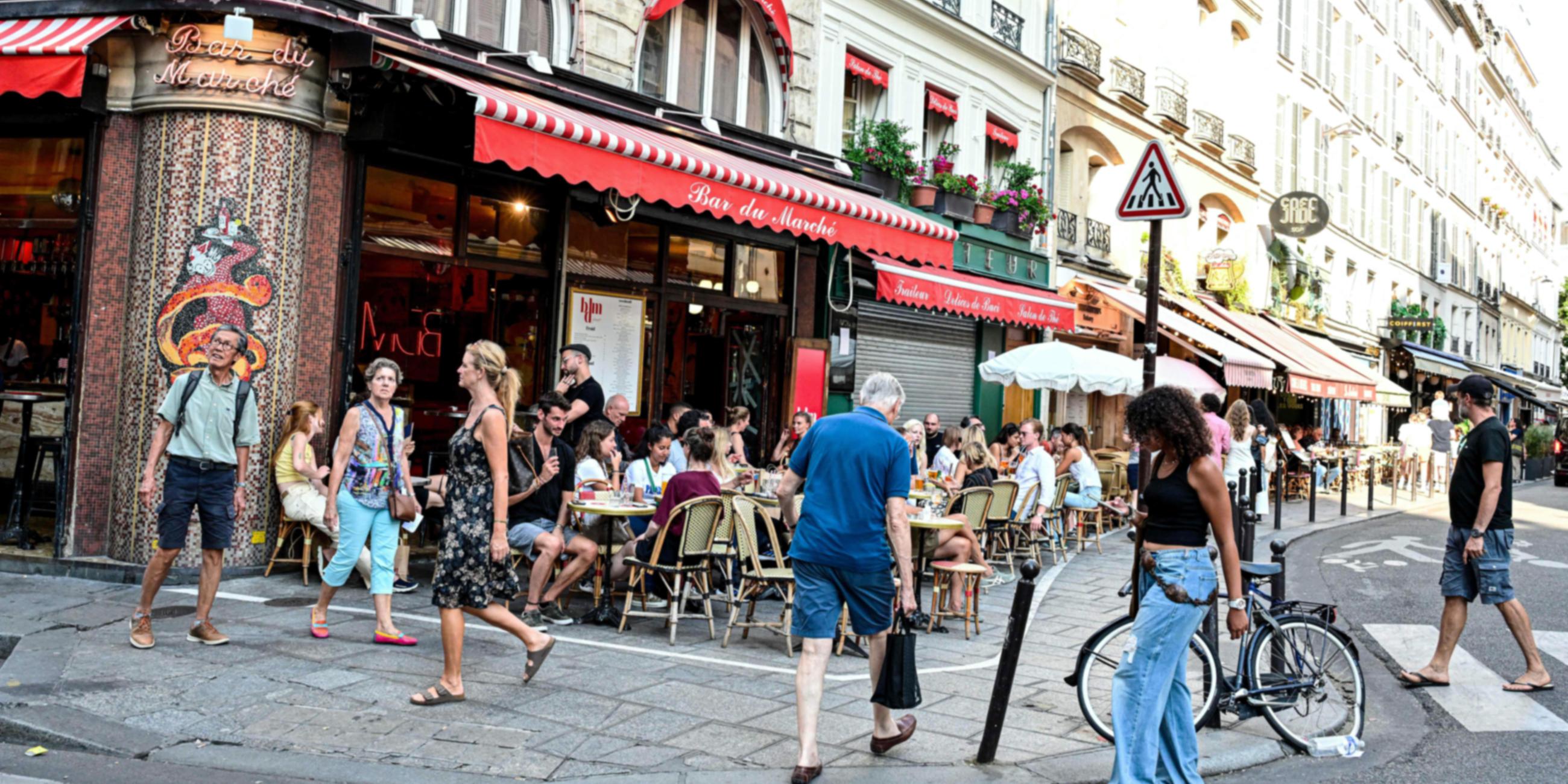 Touristen und Einheimische sitzen auf der Terrasse einer Pariser Bar.