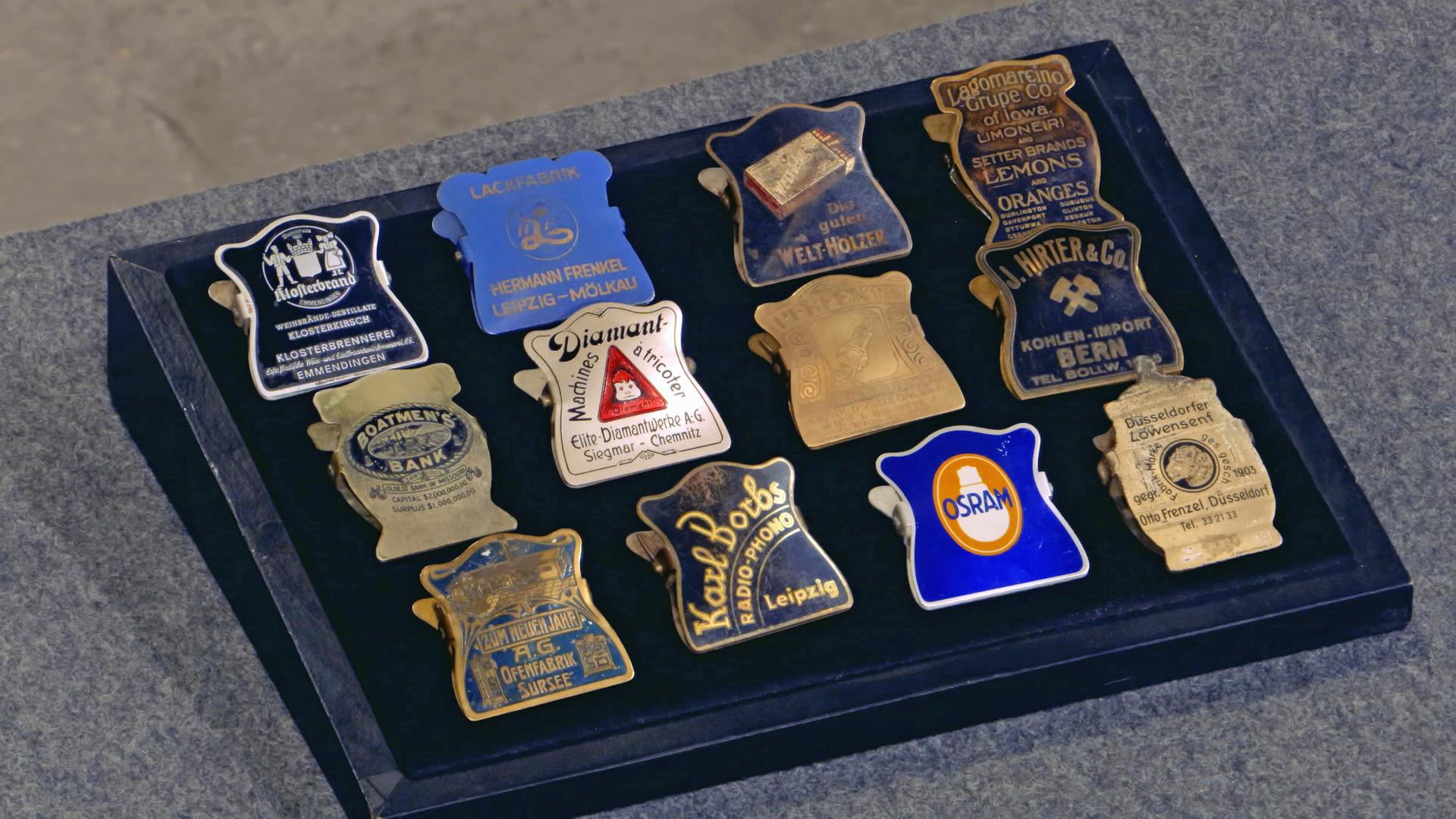 Zwölf Dokumenten-klammern mit Werbung (1910er-1930er Jahre).