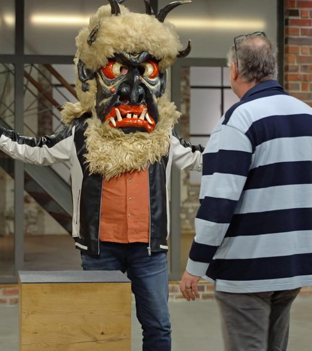 Jos van Katwijk probiert mit Walter Lehnertz Hilfe eine Krampus-Maske aus Österreich an.