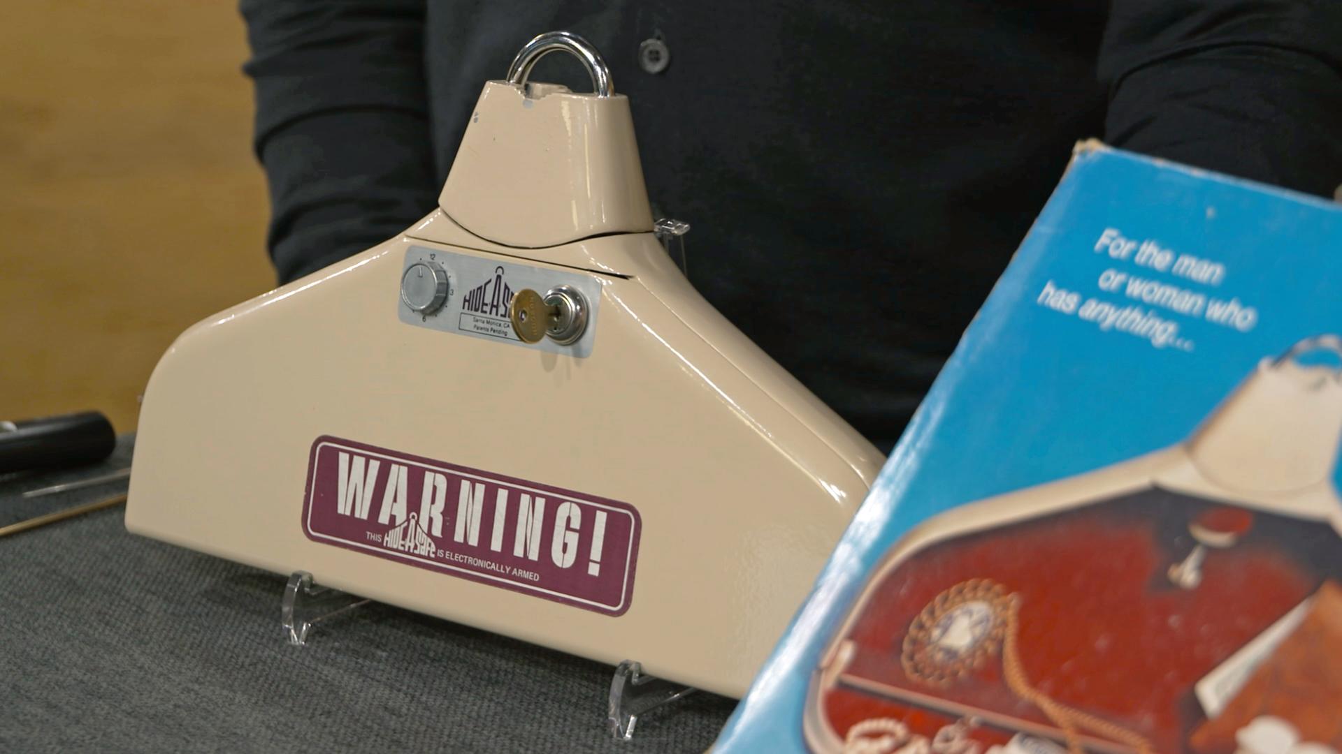 Antiker Kleiderbügel in der Farbe beige mit der Aufschrift "Warning!".