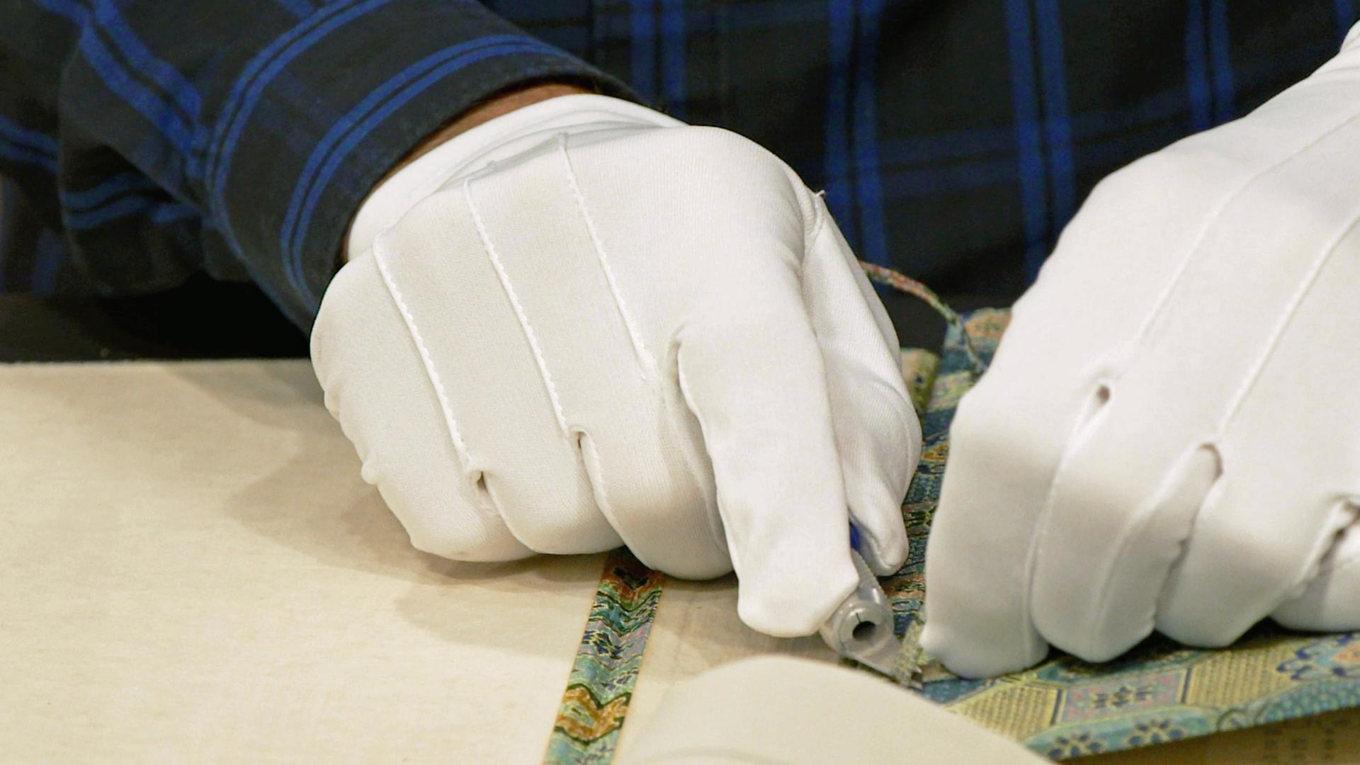 Ein altes chinesisches Handbuch über Kalligrafie wird für die Expertise von Detlef Kümmel mit Hilfe eines Messers begutachtet. 