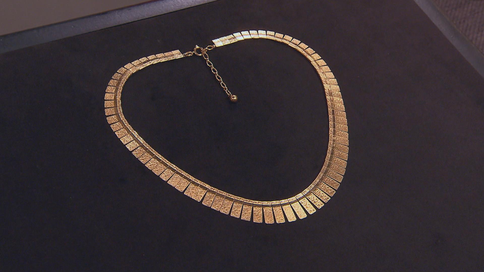 Ein Goldcollier auf schwarzem Untergrund.