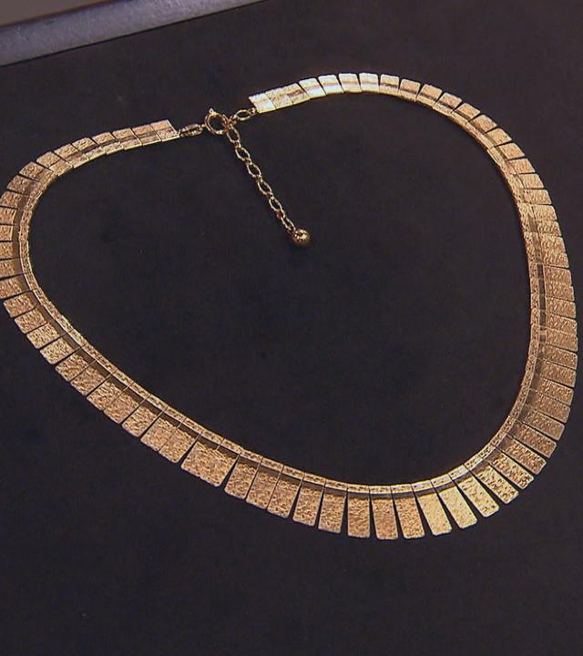 Ein Goldcollier auf schwarzem Untergrund.