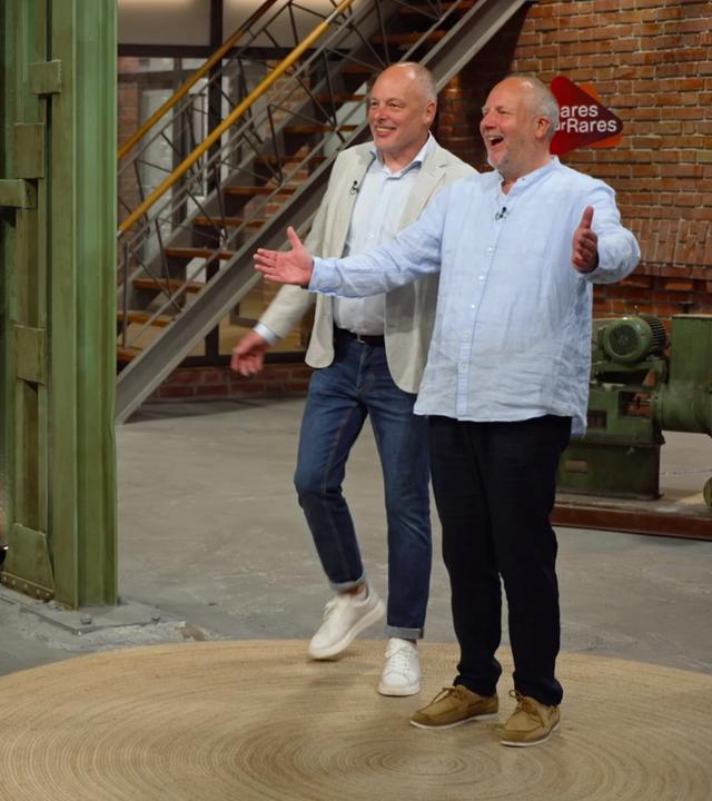 Im Händlerraum stehen rechts zwei Verkäufer und links eine menschengroßer Playmobil-Polizist.