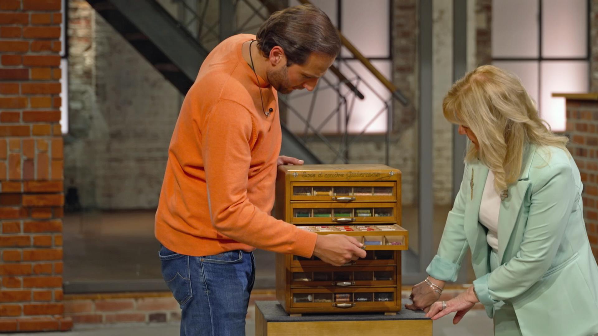 Julian und Elke begutachten im Händlerraum einen kleinen Schrank für Garne aus der Nähe. 