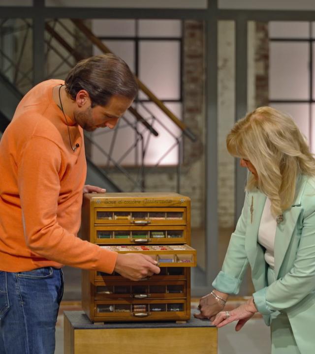 Julian und Elke begutachten im Händlerraum einen kleinen Schrank für Garne aus der Nähe. 