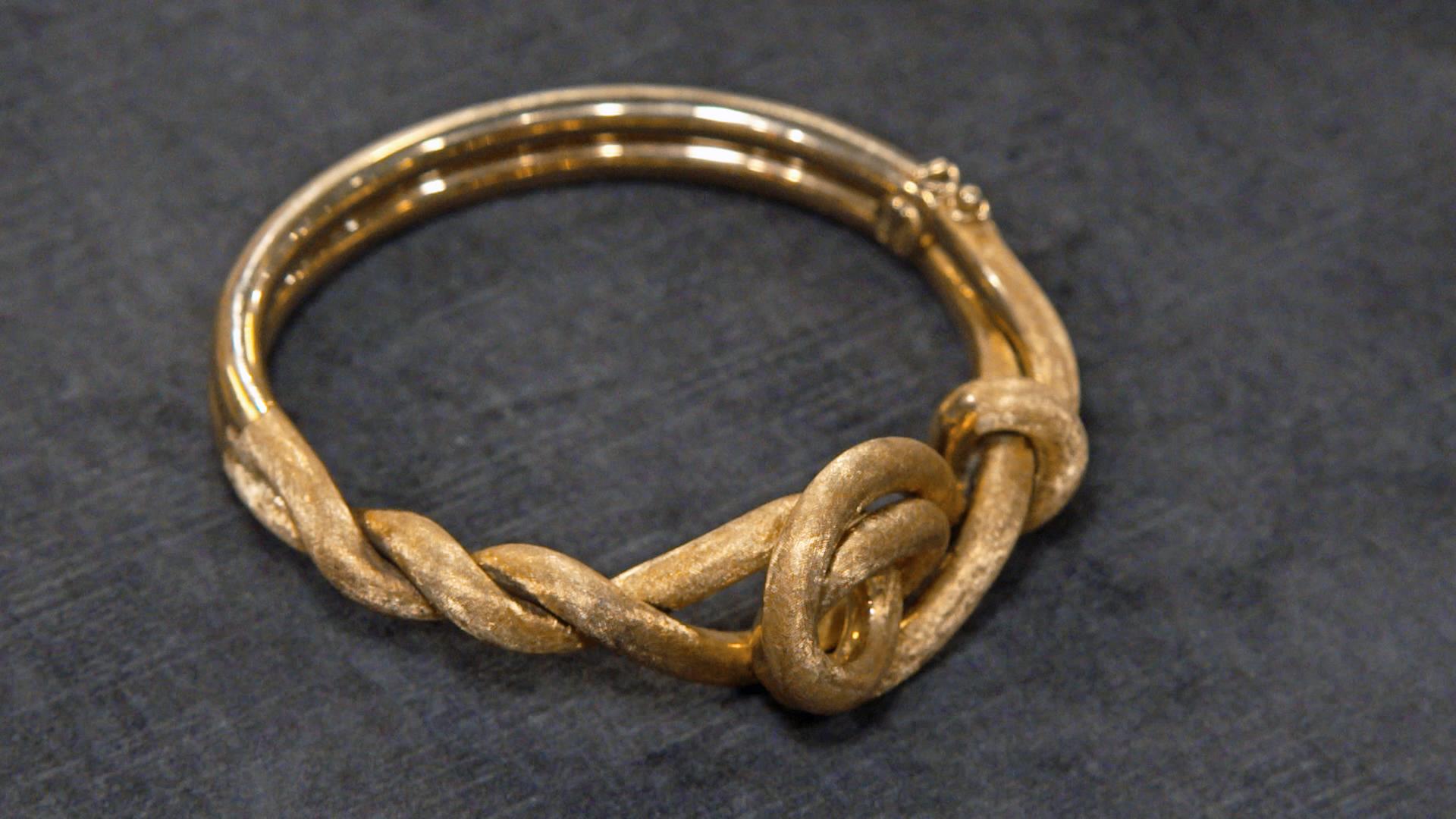 Ein goldener Armreif in Kreuzknotenform 