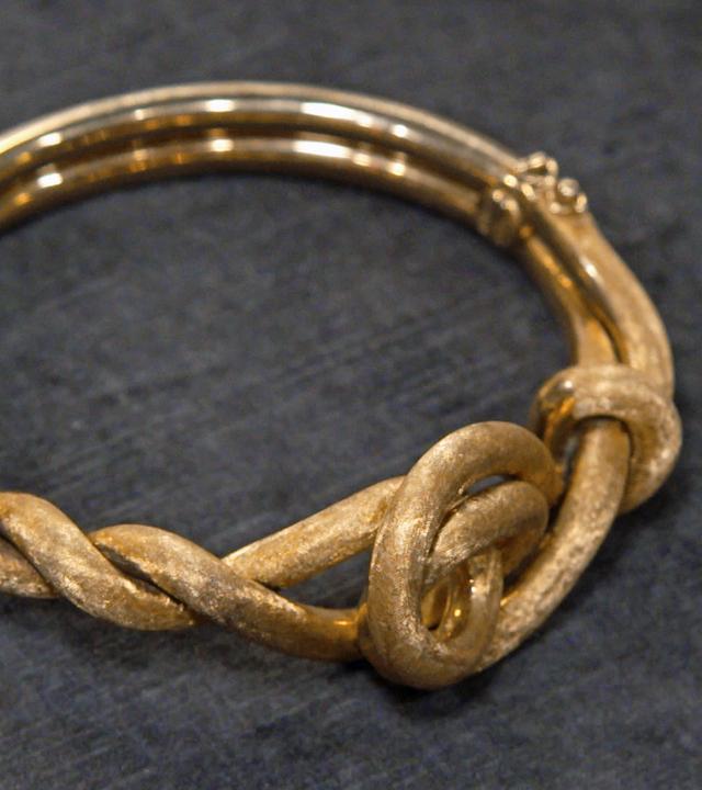 Ein goldener Armreif in Kreuzknotenform 