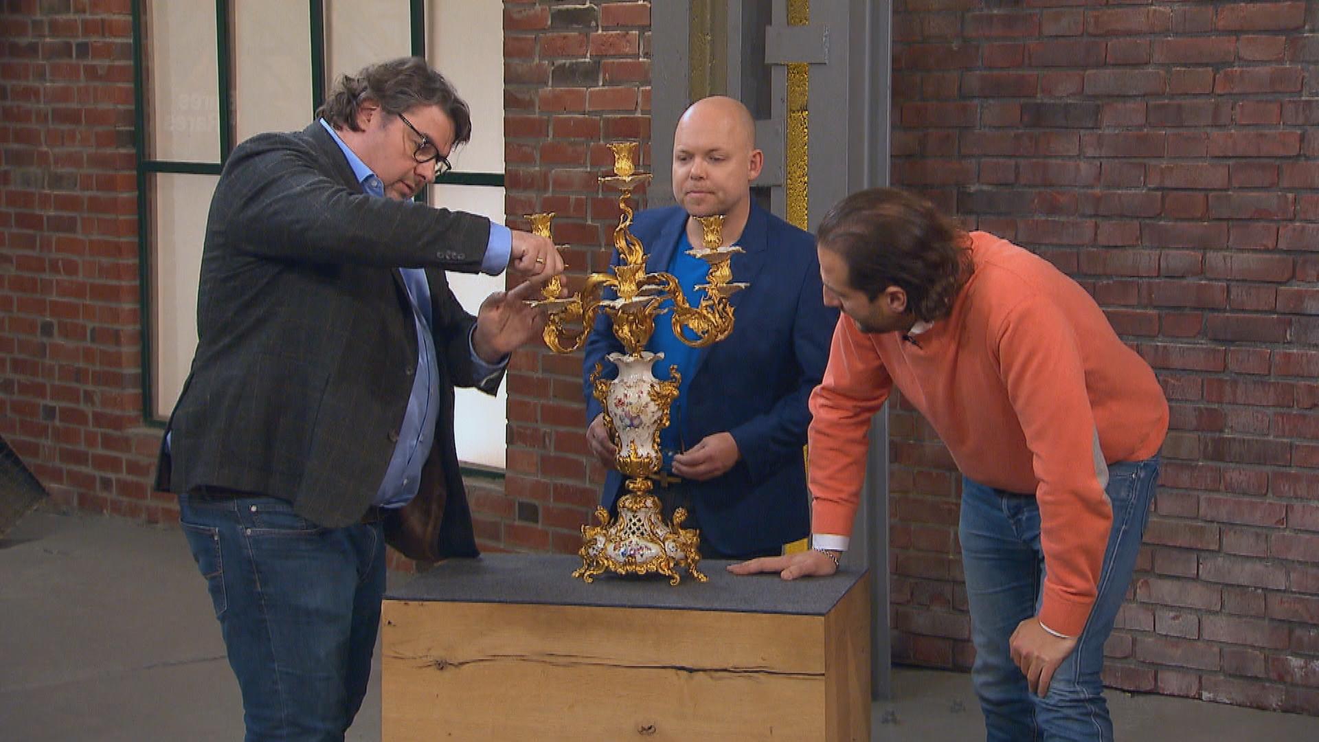 Die Händler Daniel Meyer, Benjamin Leo Leo und Julian Schmitz-Avila begutachten im Händlerraum einen Kandelaber von KPM