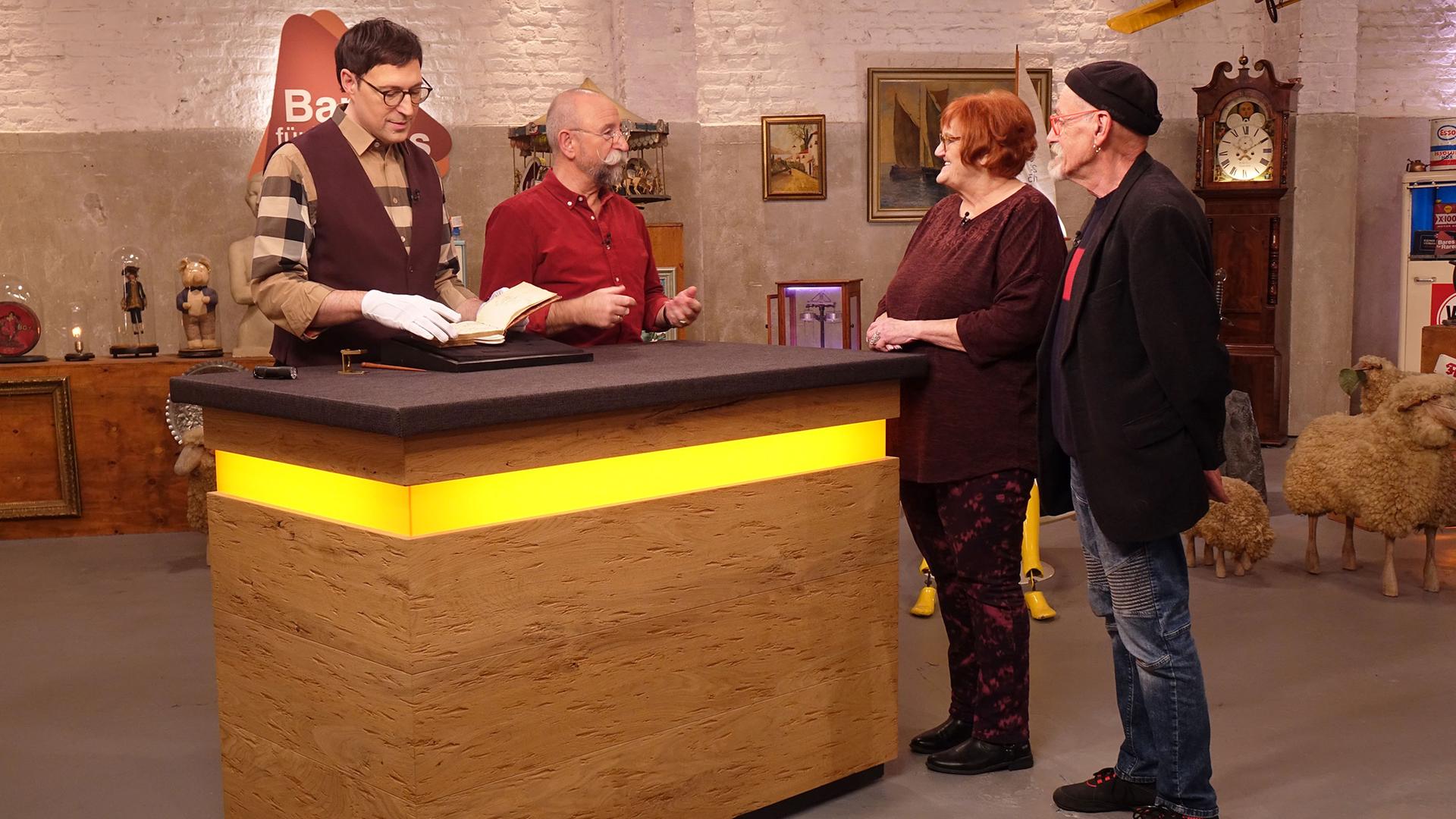 Experte Colmar Schulte-Goltz begutachtet ein Poesiealbum. Neben ihm am Expertentisch stehen Horst Lichter, die Verkäuferin und der Verkäufer.