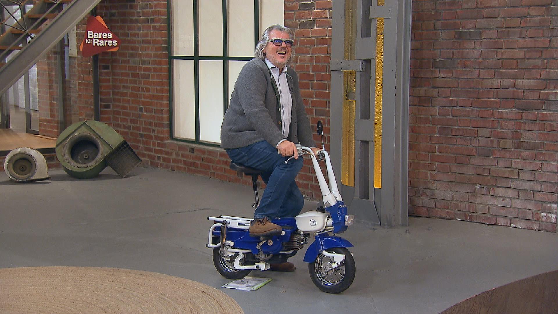 Händler Roman Runkel sitzt auf einem Koffer-Moped