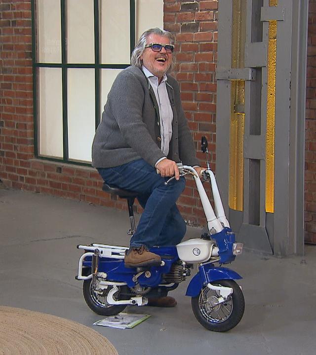 Händler Roman Runkel sitzt auf einem Koffer-Moped