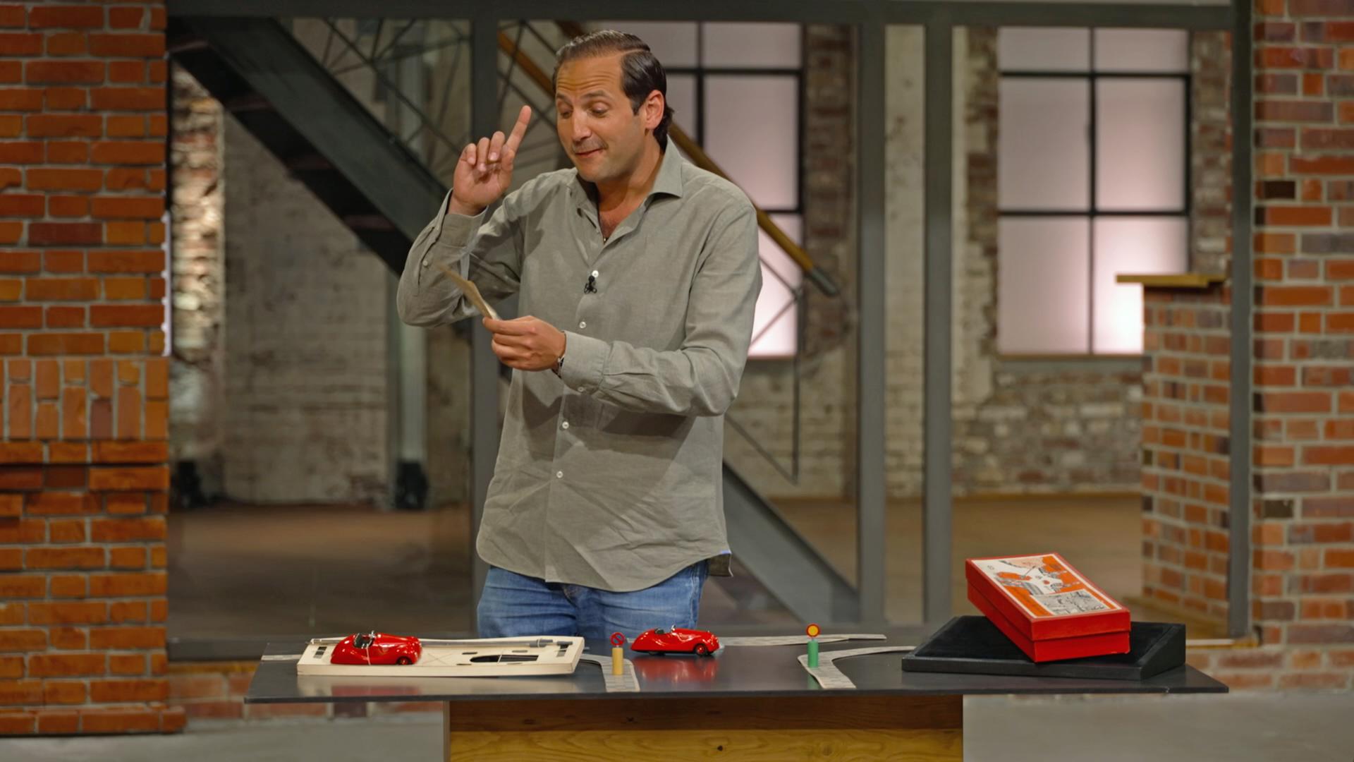 Händler Julian spielt mit einem Fahrschule-Spiel von Schuco und stellt Wirklichkeitsfragen in die Händlerrunde.