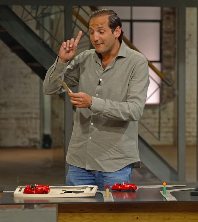 Händler Julian spielt mit einem Fahrschule-Spiel von Schuco und stellt Wirklichkeitsfragen in die Händlerrunde.