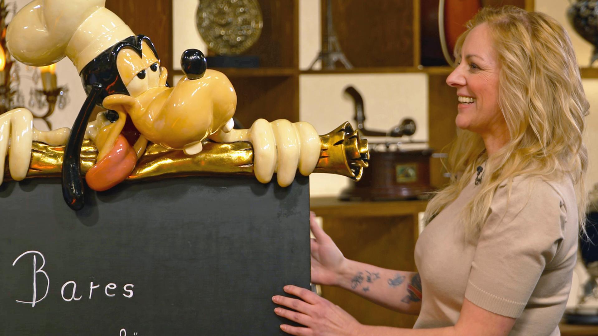 Annika Raßbach begutachtet eine Restauranttafel mit einer Goofy-Figur.