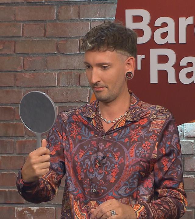 Händler Fabian Kahl betrachtet sich in einem Handspiegel.