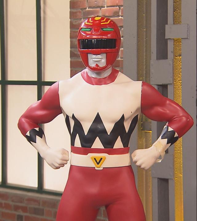 Ein lebensgroßer roter Power Ranger und Händler David Suppes, der jubelnd die Arme in die Luft reißt