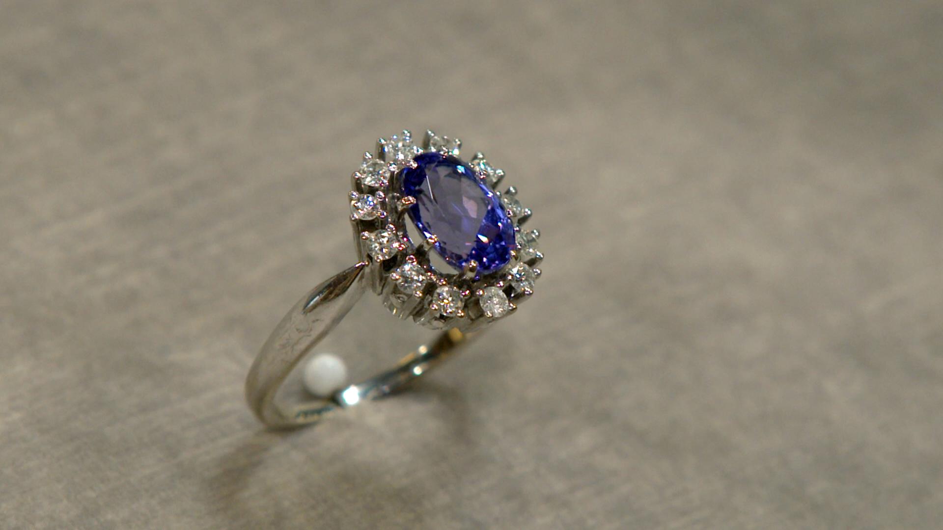 Goldring mit einem lilanen Tansanit-Stein, umrandet von kleinen Brillanten.