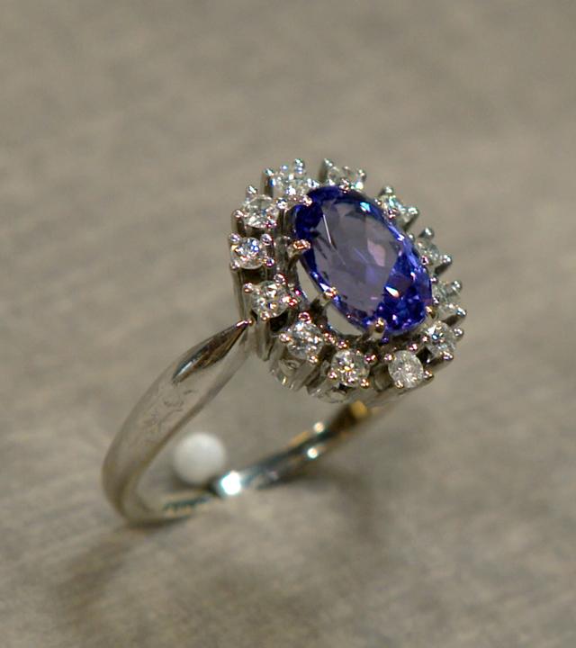 Goldring mit einem lilanen Tansanit-Stein, umrandet von kleinen Brillanten.