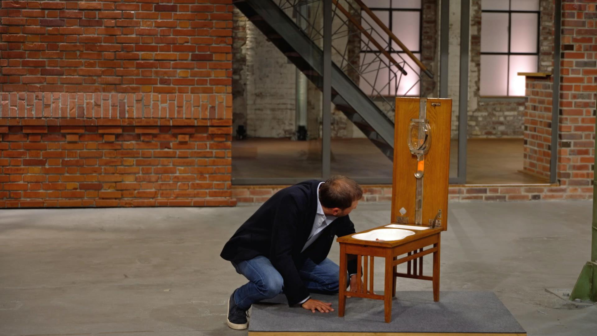 Julian Schmitz-Avila begutachtet ein antikes Klapp-Bidet.